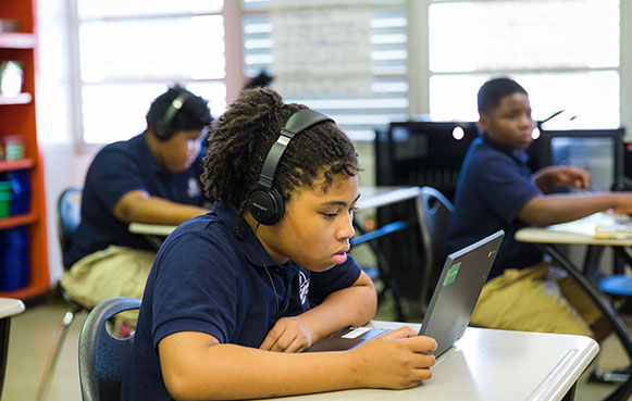 students in classroom working on laptops