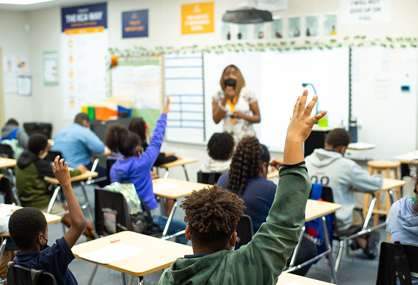 students raising hands in classroom