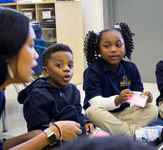 young students in classroom sitting on floor and learning