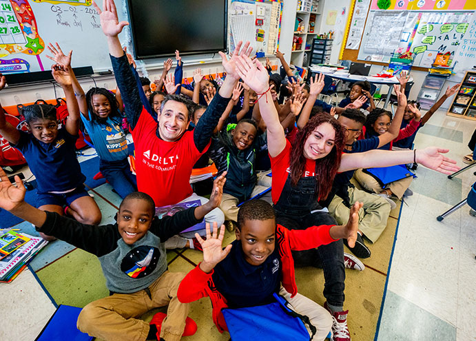 group of students in classroom waving and smiling