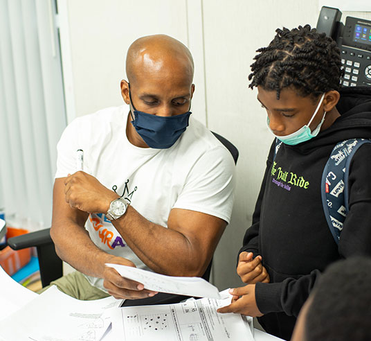 student and teacher in classroom looking at papers