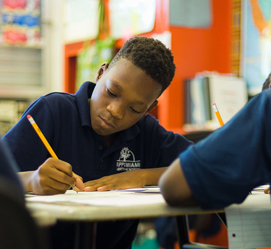 student in classroom writing