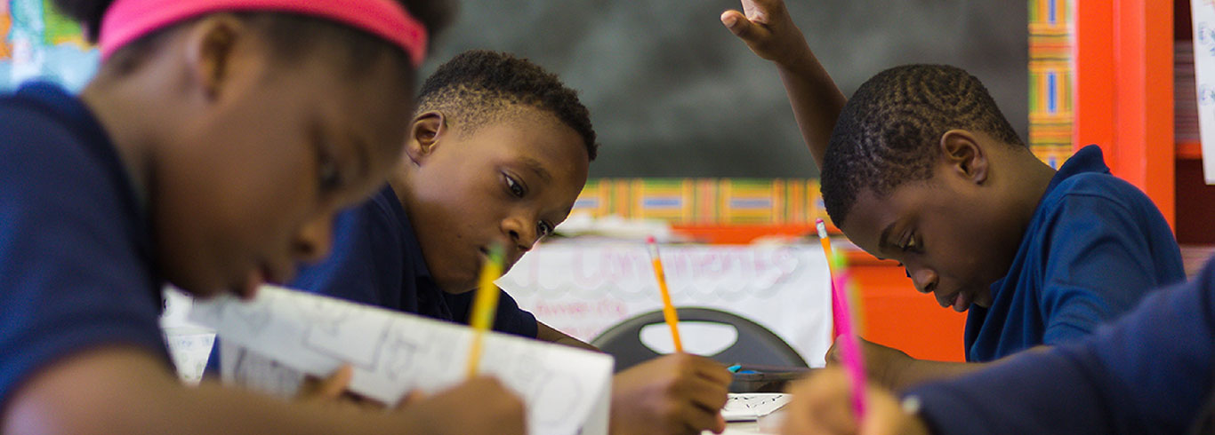 students in classroom writing while sitting in desks