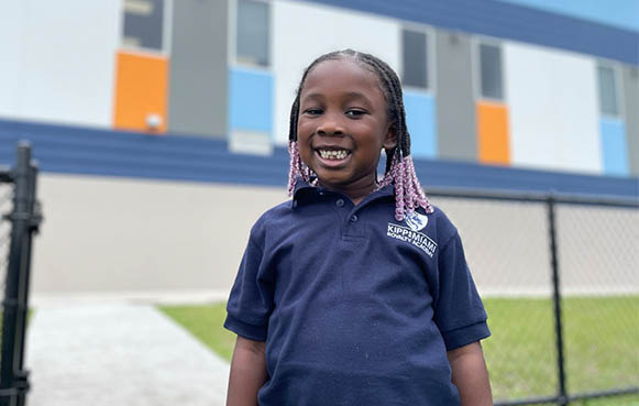 student in front of school smiling