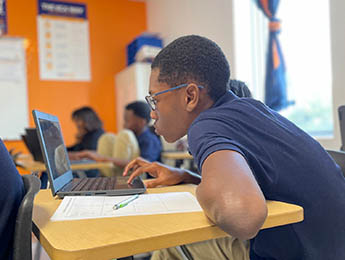 student in classroom working on laptop