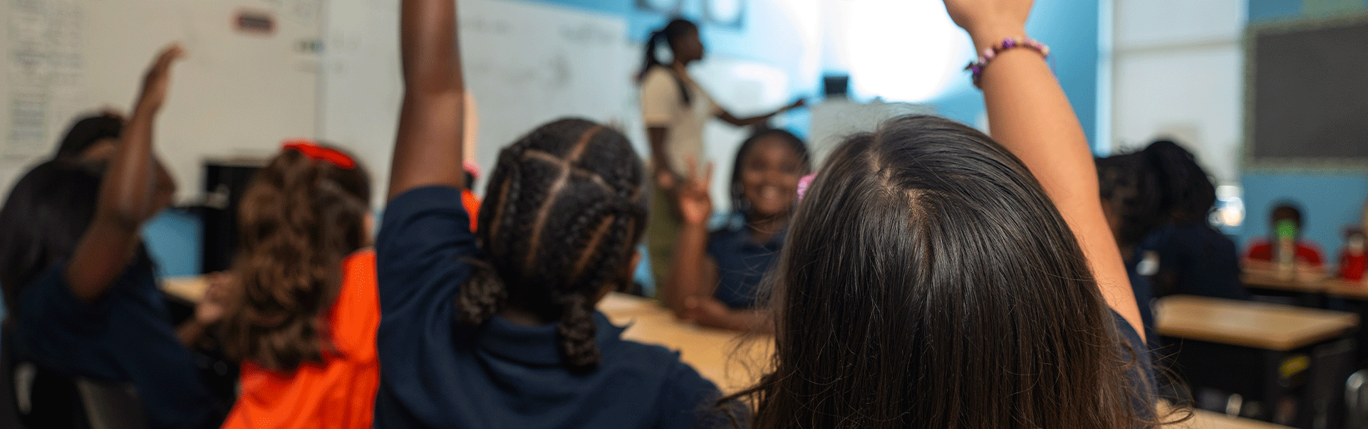 Students in classroom with hands raised